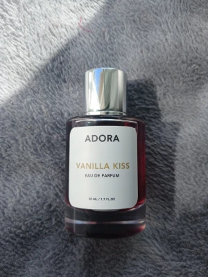 Adora Vanilla Kiss Eau de Parfum🤍🌼 - Adora Vanilla Kiss Eau de Parfum är en parfym i en elegant, rund glasflaska med silverfärgad spraykork. Doften har en tydlig vaniljkaraktär och flaskan rymmer 50 ml. Etiketten är vit med guld- och svart text, vilket ger ett stilrent intryck. Om du älskar vanilj så är det perfekta doften🥰😍