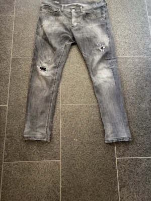 Mörkgråa Dondup jeans  - Snygga jeans från Dondup i grå, tvättad look. Skinny fit med stretch för en bekväm och följsam passform. Trendigt slitna detaljer vid knäna som ger en modern, avslappnad stil. Storlek 33. Kan gå ner i pris under snabb affär!