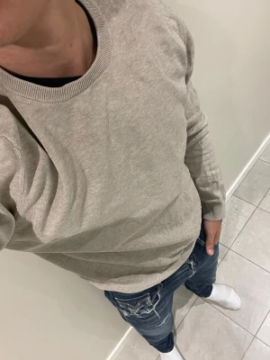 Beige stickad tröja från bläck - Snygg beige stickad tröja från Selected Homme med rund halsringning och ribbade muddar vid ärmslut och nederkant. Perfekt för lager-på-lager och passar till både jeans och chinos. Enkel och stilren design som funkar året runt. 💋Modellen bär storlek L och är 181 cm lång och väger 76 kg kom gärna vid frågor eller funderingar💋