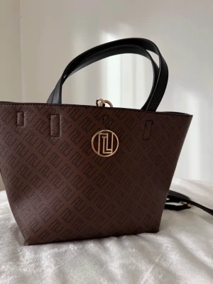 THERNLUNDS HANDVÄSKA  - Brun mönstrad tote handväska från Thernlunds, tillkommer även med justerbar axelband. Gammal modell, nypris 1499kr.