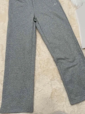 Grå mjukisbyxor från Alo Yoga M (38) - Snygga grå mjukisbyxor från Alo Yoga med raka ben och elastisk midja. Byxorna har en diskret logga framtill 