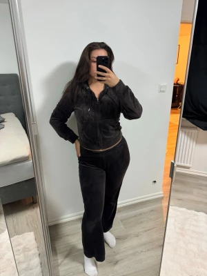 Bruna mjukisset  - Säljer ett svart mjukisset i velour med zip-hoodie och matchande byxor med raka ben. Hoodien har dragkedja, fickor och snörning i huvan. Byxorna har resår i midjan för skön passform. Perfekt för chill dagar hemma eller när du vill vara extra comfy.