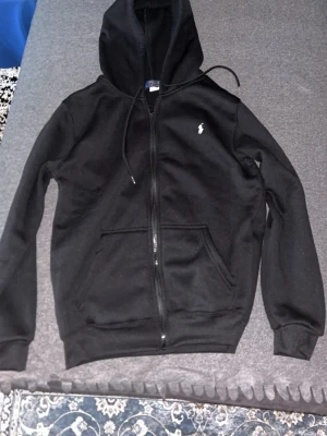 Hoodie Ralph Lauren - Svart hoodie med dragkedja från Polo Ralph Lauren. I storlek S men kan passa M