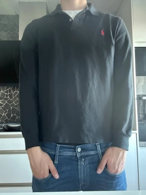 Svart långärmad pikétröja Ralph Lauren - Svart långärmad pikétröja från Ralph Lauren i ett dunder skick! Inga skador eller hål på tröjan och helt perfekt nu inför sommaren.