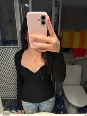 Svart ribbad v-ringad topp H&M - Svart långärmad topp från H&M med v-ringning och ribbad struktur. Sitter tight och har en smickrande passform som framhäver figuren. Perfekt att styla med jeans eller kjol för en trendig look.