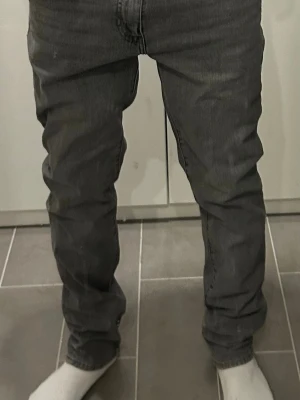 Grå Levi's straight fit jeans - Säljer ett par gråa Levi's jeans med rak passform och klassiska fem fickor. Jeansen har en snygg tvättad look, normal midja och Levi's ikoniska läderpatch bak i midjan. Tillverkade i slitstark bomull, perfekta för en avslappnad stil.