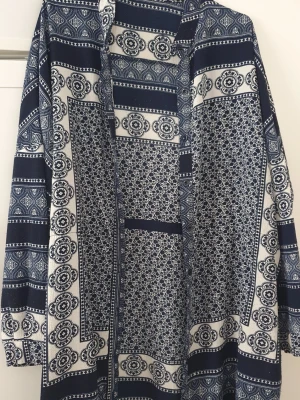 Klänning - Säljer en långärmad långklänning från Boohoo med marinblå och vita detaljer. Klänningen har ett unikt rutigt och blommigt mönster som ger en cool boho-vibe. Perfekt för dig som gillar att sticka ut med stilrena mönster och färger. Lite noprigt.