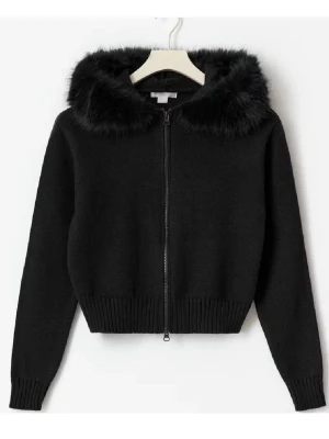 Svart hoodie med fuskpäls - Svart stickad hoodie med dragkedja och mjuk fuskpäls runt huvan. Tröjan har ribbade muddar och en croppad passform. Perfekt för en trendig och mysig look.