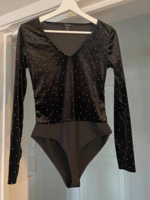 Svart sammetsbody  - Snygg svart body i sammet med lång ärm och djup V-ringning. 