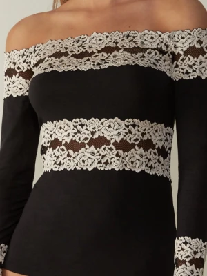 Svart offshoulder topp med spets från Intimissimi - Trendig svart offshoulder topp med långa ärmar och vita spetsdetaljer runt axlar, midja och ärmslut. Toppen har en figurnära passform och ger en elegant look med sina kontrasterande spetsband. Perfekt för dig som vill sticka ut med stil.