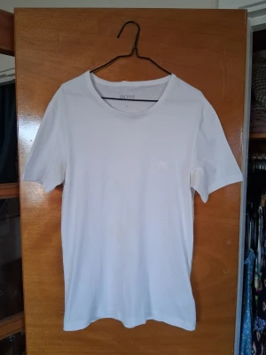 Vit t-shirt från BOSS - Snygg vit t-shirt från BOSS med diskret logga på bröstet. Klassisk rund halsringning och korta ärmar. Perfekt för en clean och stilren look! 😃 Några mindre, knappt synliga fläckar som går att tvätta bort.