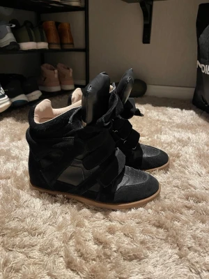 Isabell marant  - Snygga svarta sneakers med högt skaft och breda kardborreband. Skorna har en mix av mocka och läderdetaljer samt en beige insida. Dom är i bra skick och snålt använda! Storlek 39