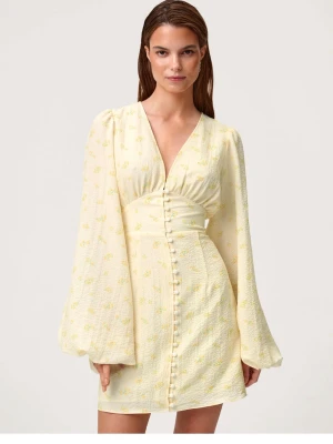 Ljusgul kortklänning med blommigt mönster - Söt ljusgul kortklänning med små blommor, v-ringad och med knappar framtill. Klänningen har långa, vida ärmar och markerad midja som ger en snygg siluett. Perfekt för sommarens alla tillfällen.