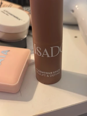 Isadora Contour Stick Bronzer - Krämig contour stick från Isadora i en 34 dark almond. Perfekt för att skulptera och definiera ansiktet. Enkel att applicera tack vare den smidiga stiftformen. Förpackningen är cylinderformad i plast med vit text. Den är använd typ två gånger men kommer ej till användning o ja kommer torka av den o sanitera den innan jag skickar