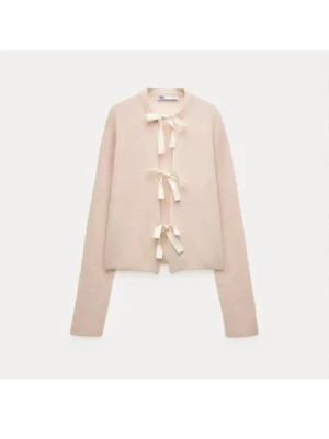 Beige kofta med rosettknäppning - Söt beige kofta från ZARA med tre dekorativa rosettknäppningar framtill. Koftan har lång ärm och är gjord i ett mjukt stickat material som känns riktigt comfy. Perfekt för dig som gillar en feminin och trendig look.