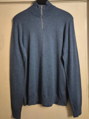 Blå quarter zip - Säljer en helt oanvänd blå stickad quarter zip från Lindbergh. Den är S men är lite stor.