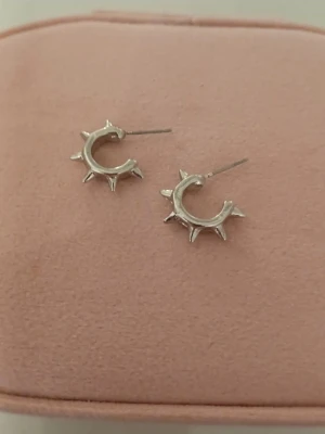 Silvriga örhängen med spikar  - Säljer ett par silvriga örhängen med spikdetalj. Örhängena har en modern och stilren design som passar perfekt för dig som gillar unika accessoarer. Materialet ser ut att vara metall i silverfärg.❣️❣️