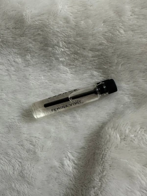 Femina Vivit parfymprov essnce  - Litet parfymprov från Femina Vivit i genomskinlig glasflaska med svart skruvkork. Flaskan är cylinderformad och har enkel, stilren text på sidan. Perfekt att ha med i väskan för en fräsch doft när som helst.
