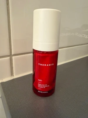 Theramid Azid kräm - Säljer en Theramid Azid ansiktsbehandling i en snygg röd plastflaska med vit kork. Innehåller azelainsyra 15%, kolloidalt havre 3% och centella 1%. Flaskan rymmer 30 ml, jag skulle uppskatta att det är 70 procent av flaskan kvar. 