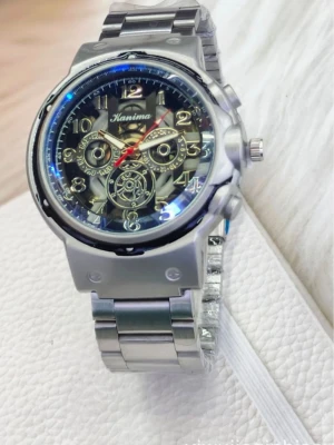 Silverfärgad klocka från Hanima - Råka beställa 2st båda e pö väg helt ny skriv innan ni köper så jag kan se när det är här. Stilren klocka från Hanima i silverfärgat metallarmband och boett. Urtavlan har synliga kugghjul och detaljer i guld och svart, samt siffror i silver. Klockan har flera dekorativa små urtavlor och en röd sekundvisare.