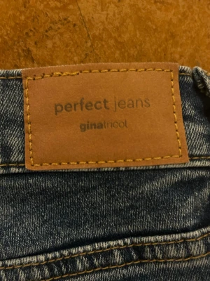 Blå Perfect Jeans från Gina Tricot - Säljer ett par klassiska blå jeans från Gina Tricot, modellen Perfect Jeans. De har normal midja, raka ben och snygga kontrastsömmar. Perfekta till vardagslooken och superenkla att matcha med olika stilar.
