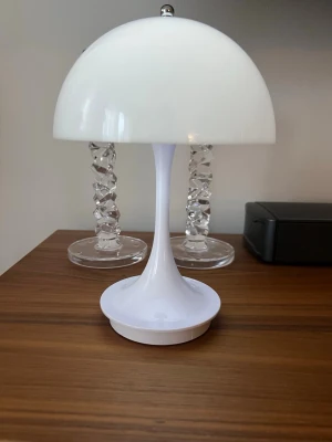 Panthella stil bordslampa – ej original - Säljer en stilren vit bordslampa med svampformad design. Lampan är tillverkad i plast och har en rund, kupolformad skärm samt en smal fot. Perfekt som dekorativ belysning i hemmet.