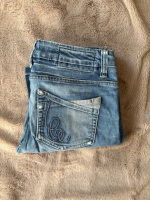 Vintage jeans - PRIS GÅR ATT DISKUTERA. Säljer ett par ljusblå vintage jeans med snygg broderad detalj på bakfickan. Klassisk femficksmodell med normal midja och raka ben. Jeansen har slitningar vid benslut och är perfekta för en avslappnad stil. Köpta mellan 1985-2005 så därav går dom inte längre att få tag på💗Midjemått: 40cm, Innerbenslängd: 78cm, Lårmått: 21cm