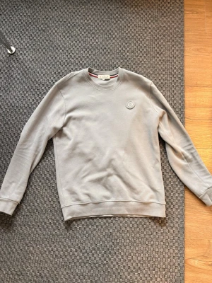 Ljusgrå sweatshirt från Moncler - En stilren ljusgrå sweatshirt från Moncler med rund halsringning och diskret Moncler-logga.