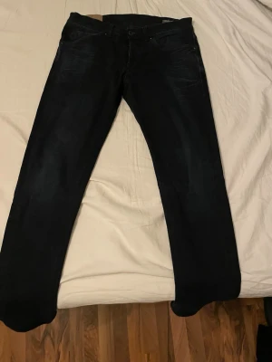 Mörkblå donup jeans slim fit  - Säljer ett par mörkblå jeans med rak passform och klassisk femficksdesign. Jeansen har subtila slitningar och är tillverkade i ett mjukt denimtyg. Perfekta för dig som gillar en enkel och stilren look.