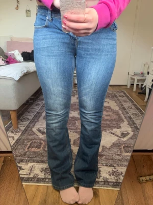 lågmidjade blå bootcut jeans  - Säljer ett par blåa bootcut jeans med klassisk femficksmodell. Jeansen har låg midja och är tillverkade i ett stretchigt denimtyg som sitter snyggt över höfterna och låren. Perfekta för en avslappnad och trendig look. Säljer pga för små. I storlek 36.