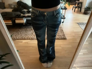Blå bootcut jeans med mörk blåa streck - Säljer ett par blå bootcut jeans med snyggt mörkblått mönster. Jeansen är från Weekday och är lågmidjade och ganska lose. Innerbenslängden=82cm, midjemått=78cm