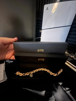 Guldfärgat kedjearmband från kejsar!😍 - Säljer ett snyggt kejsar armband 10mm från kejsar med tvinnad kedjedesign. Armbandet har en exklusiv känsla och levereras i original ask med logga. Perfekt accessoar för att lyfta din stil och ge en lyxig touch till outfiten.