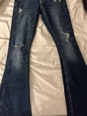 Mörkblå bootcut jeans med slitningar - säljer dessa skitsnygga mörkblåa jeansen då de tyvärr inte passar! de var för stora på mej och lappen är redan avdragen, jag har därför inte använt de en enda gång! skulle kunna gå ner i pris men inte för mycket❤️ storlek xs 14+ (tall)