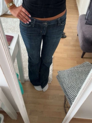 Mörkblå bootcut jeans - Snygga mörkblå bootcut jeans med klassisk femficksdesign och låg midja. Jeansen har en lätt tvättad look och raka ben som går ut lite nertill. Perfekta till en avslappnad stil.