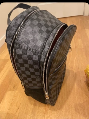 Svart grå rutig ryggsäck - Snygg ryggsäck med mönster. Väskan är svart och grå med flera dragkedjefack. Väskan är i topp skick, tveka inte på frågor! 