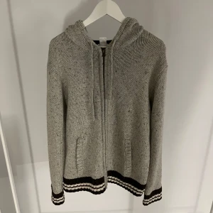 Grå stickad hoodie med dragkedja - Säljer en snygg stickad tröja/kofta i storlek M/L, perfekt till våren! Skicket är bra. Hör av dig vid funderingar!