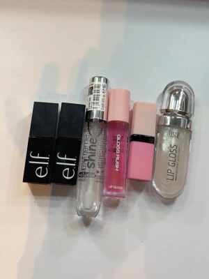 Mix av läppglans från elf, Essence & Wish - Säljer ett kit med fem läppglans i olika färger och former. Två från elf i svart fyrkantig förpackning, ett genomskinligt gloss från Essence, ett rosa gloss i söt rosa hylsa och ett glittrigt transparent gloss från Wish i rundad förpackning. Perfekt för dig som vill testa olika looks!