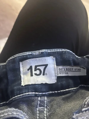 Bootcut jeans från 157, mörkblå - Snygga mörkblå bootcut jeans från 157 med 90-talsvibbar. Jeansen har klassisk femficksdesign, kontrastsömmar och utsvängda ben. Perfekta för dig som gillar retrostil och vill ha ett par jeans med lite extra attityd.