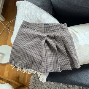 Miniskirt från Gina Tricot - Rutig kort kjol från Gina Tricot i brunt och svart. 🤎Kjolen har ett klassiskt veck framtill och har endast använts en gång.