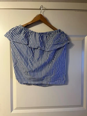 Randig offshoulder topp med volang - Säljer en blåvit randig offshoulder topp från Hm i stolek 40🙌🏻 Jöttefin blus nu till sommaren och den är i helt oanvänt skick😊