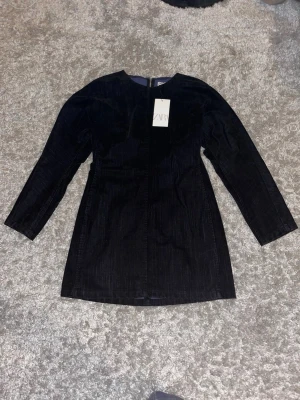 Oanvänd svart klänning från ZARA - Snygg svart kortklänning från ZARA. Klänningen har lång ärm och en figurnära passform som ger en stilren look. Perfekt för dig som gillar minimalistisk stil och vill ha något enkelt men ändå trendigt. Den är oanvänd och prislapp finns kvar. Orginalpris 699.
