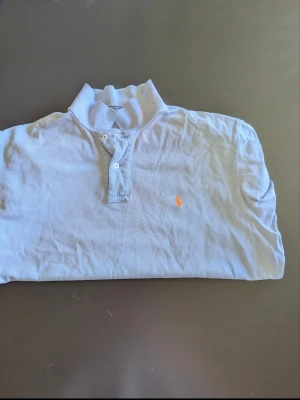 Ralph Lauren piketröja - Ljusblå pikétröja från Ralph Lauren med korta ärmar och krage. Har inga problem och inga fel märks.