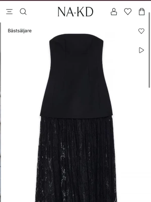 Svart axelbandslös spetsklänning NA-KD - Trendig svart axelbandslös klänning från NA-KD med figurnära överdel och lång, transparent kjol i spets. Aldrig använd, säljs då jag köpte tre storlekar och valde en annan. Satt något tajt på mig som egentligen har 36 i storlek. Alltså stor i storleken💕 