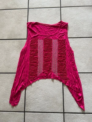 Rosa croppad topp med paljettdetaljer storlek M/L - Cool rosa croppad topp med långa ärmar och unika rynkade detaljer framtill. Toppen har tre vertikala rader med silvriga paljetter som ger extra bling. Perfekt för dig som vill sticka ut med en edgy och trendig look.