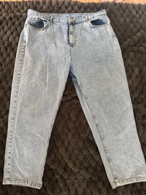 Ljusblå mom jeans med hög midja - Säljer ett par ljusblå mom jeans med hög midja och raka ben. Klassisk femficksmodell i mjukt denimtyg, perfekta för en avslappnad och trendig look. Passar till allt från sneakers till boots.