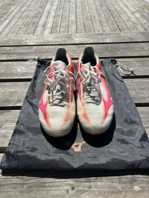Mizuno vita och rosa fotbollsskor - Mizuno fotbollskor a III JAPAN AG i storlek 42. De är vita, röda och rosa. De har använts och är lite slitna som visat på bilder. Nypris är 4000kr, priset går att diskutera och förhandla då de inte är hugget i sten! Skriv vid andra frågor! Skolåda kommer även med!