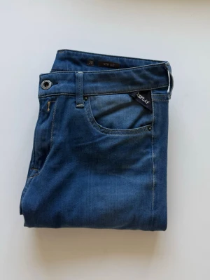 Replay Marinblå Jeans - Snygga blå jeans från Replay med klassisk femficksdesign och diskret Replay-logga på fickan. Jeansen har kontrastsömmar och en cool bakficka med broderad detalj. Materialet är mjukt denim som ger en skön passform och stilren look. Storleken är W30/L32