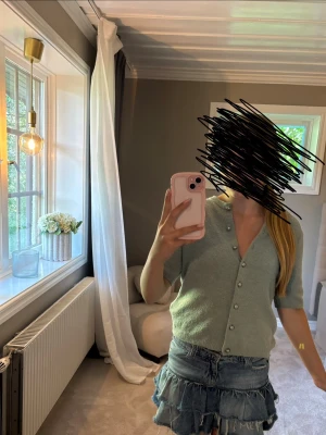 Ljusgrön stickad kortärmad topp från H&M strl XS - Superfin ljusgrön stickad topp med korta ärmar. Toppen har knappar framtill och en croppad passform som passar perfekt till jeans eller kjol. Enkel och stilren design som är lätt att matcha.