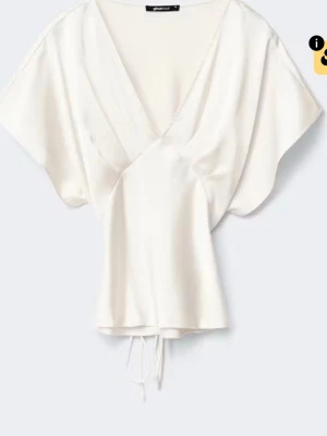 Vit omlottopp i satin - Snygg vit omlottopp från Gina Tricot i glansigt satinmaterial. Toppen har korta, vida ärmar, djup v-ringning och knytband i midjan för en feminin siluett. Perfekt att styla med jeans eller kjol för en trendig look.