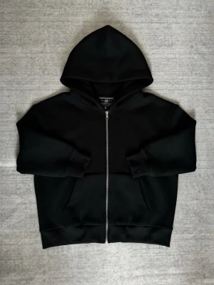 Saint Alexander Scuba Zip-hoodie - Svart scuba hoodie från Saint Alexander i storlek M. Klassisk modell med stor huva och hel dragkedja framtill. Sitter baggy så den hade dessutom passat L. Texten på taggen är lite defekt av tvätt, därav "Bra skick". Har användts fåtal gånger.